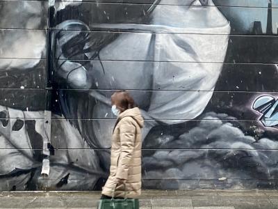 Chinese woman with mask in front of mask mural