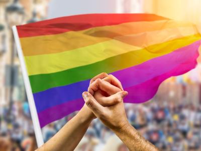 Clasped hands in front of pride flag