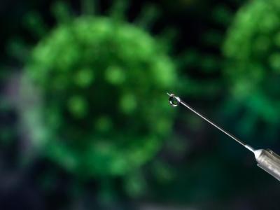 COVID vaccine syringe with virus in background