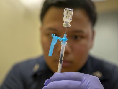 COVID vaccinator behind vial and syringe