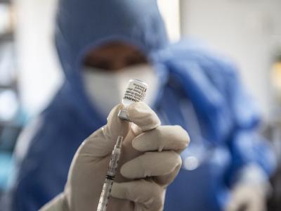 COVID vaccine with blurred healthcare worker in background