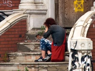 Distressed person on steps of dilapidated building