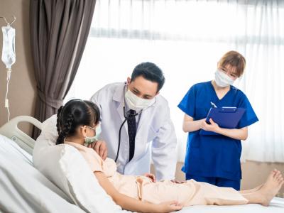 Doctor and nurse checking on girl in hospital bed