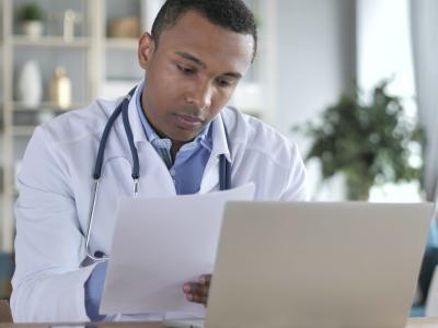 Doctor taking notes at laptop