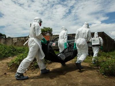Ebola workers in Liberia carry a body bag.