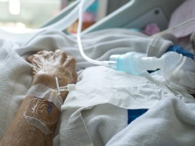 Elderly patient's hand in hospital bed