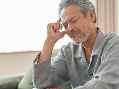 Fatigued older man sitting on couch