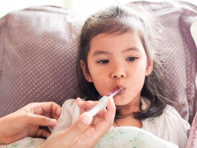 Young girl receiving oral liquid medicine