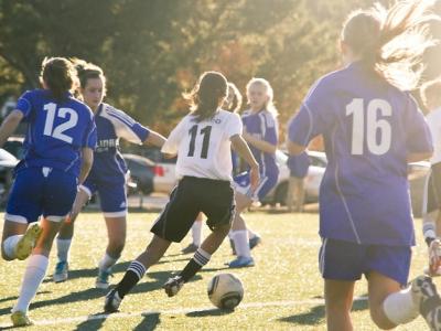 Girls playing soccer on sunny field