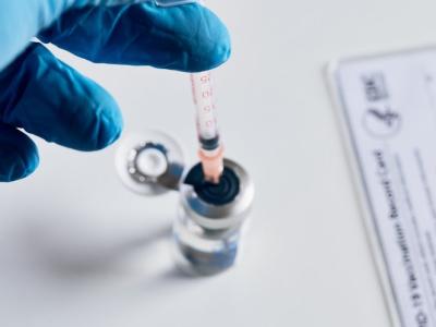 Gloved hand, vaccine vial, and vaccination card
