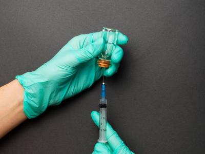 Gloved hands preparing vaccine in syringe