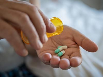 Green and white capsules in person's hand