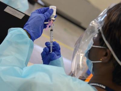 Healthcare worker filling COVID vaccine syringe