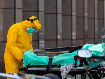 Healthcare worker in full PPE with patient on stretcher
