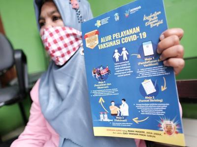 Indonesian woman with COVID pamphlet