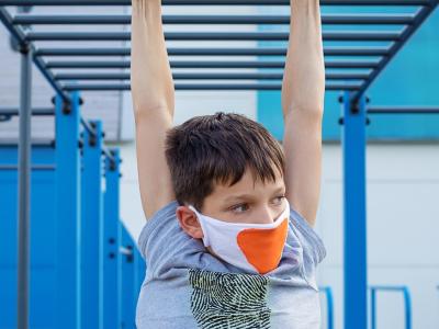 Boy wearing mask and hanging on rings