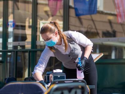 Lithuanian waitress disinfecting tables outdoors