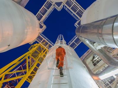 Man climbing tower at gas oil plant