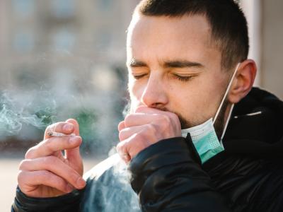Man with surgical mask smoking outside