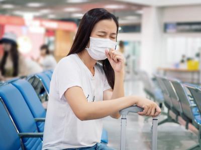 Mask-wearing tourish coughing in airport