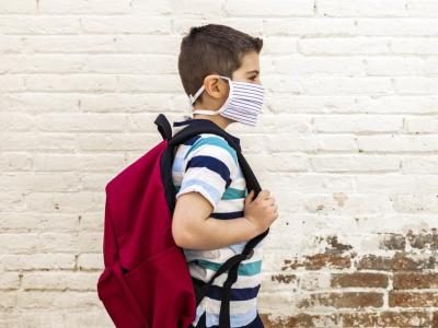 Masked school boy with backpack