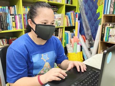 Mask-wearing student at laptop in library