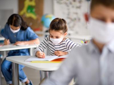 Masked schoolkids at desks