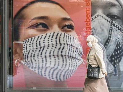 Masked woman walking in front of masking signs