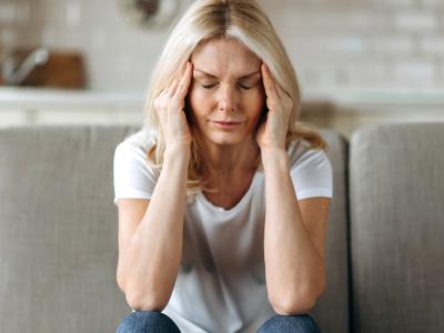 Middle-aged woman with headache sitting on couch