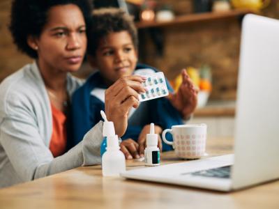 Mom holding capsules with boy at computer