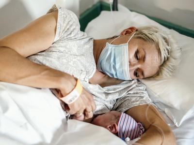 Mom wearing mask nursing newborn baby