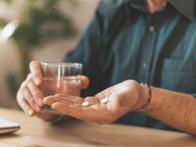 Older man taking 2 white pills