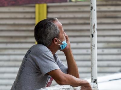 Pensive man outside with mask on chin