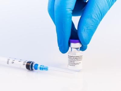 Pfizer COVID vaccine bottle with gloved hand