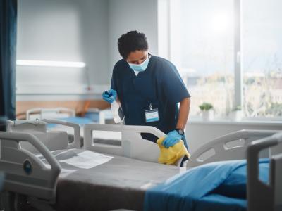 Hospital worker sanitizing hospital bed