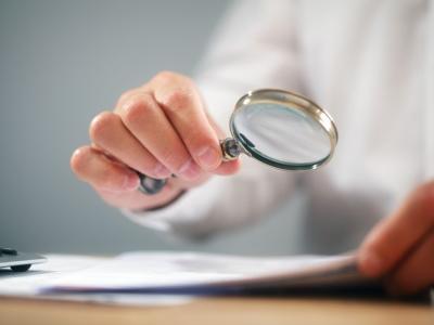 Scrutinizing report with magnifying glass