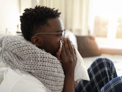 Sick man on couch blowing nose