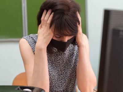 Stressed teacher wearing mask at her desk