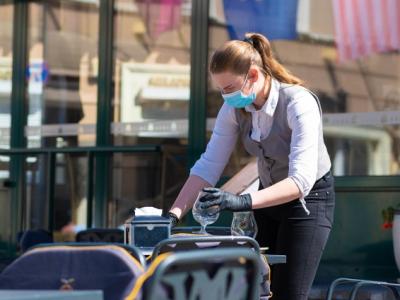 Waitress with mask disinfects tables