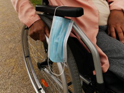 Medical mask hanging on woman's wheelcair