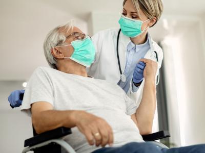 Wheelchair patient with doctor, both wearing masks