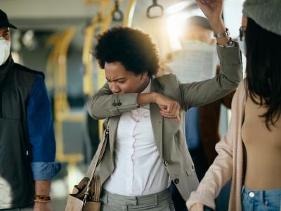 Woman coughing into sleeve on train