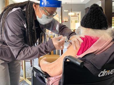 Older woman in wheelchair receiving COVID-19 vaccine