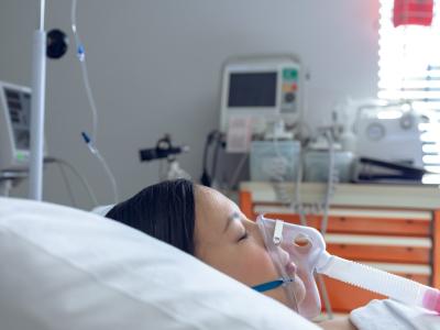 Woman in hospital bed wearing oxygen mask