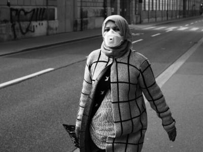 Lone woman with mask walking along street