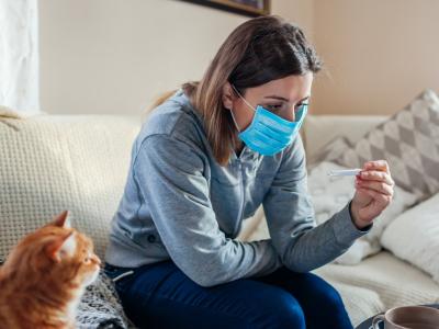 Woman wearing mask at home checking her temperature