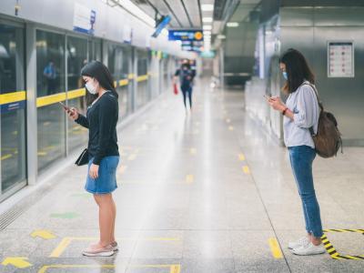 Women physically distancing at train station