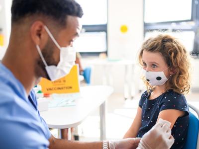 Young girl getting vaccinated, wearing mask