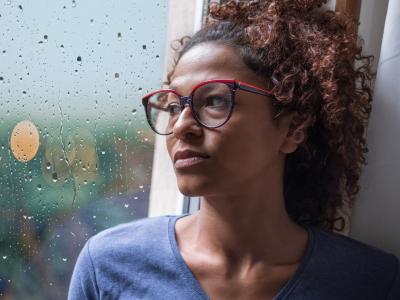 Sad young woman by rainy window
