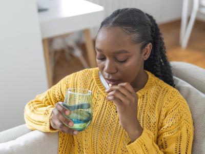 Young woman on couch taking pill